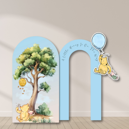 Winnie the Pooh arch backdrop with balloon and tree design for baby shower.