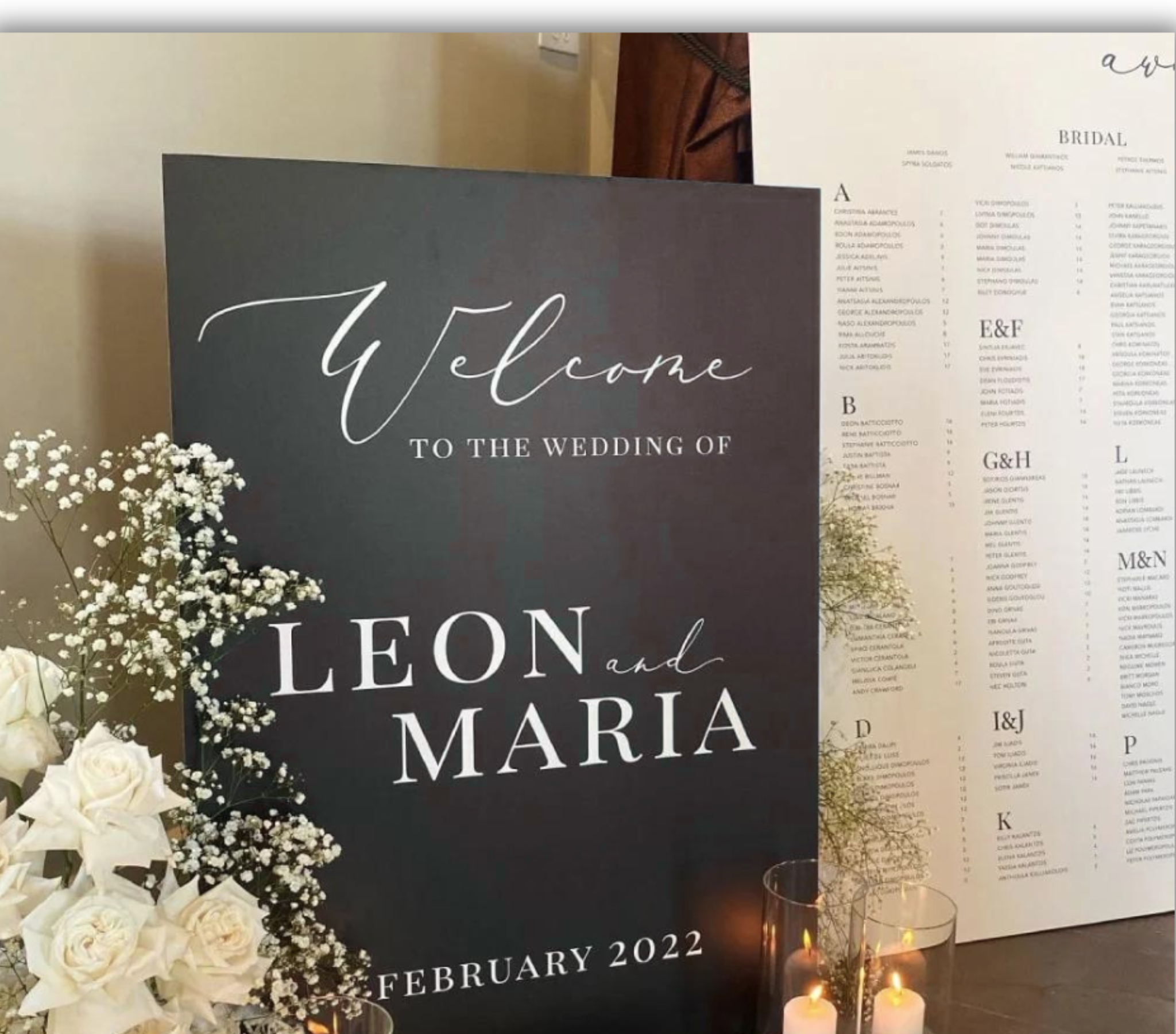 Black wedding welcome sign with the names Leon and Maria displayed beside a coordinating seating chart